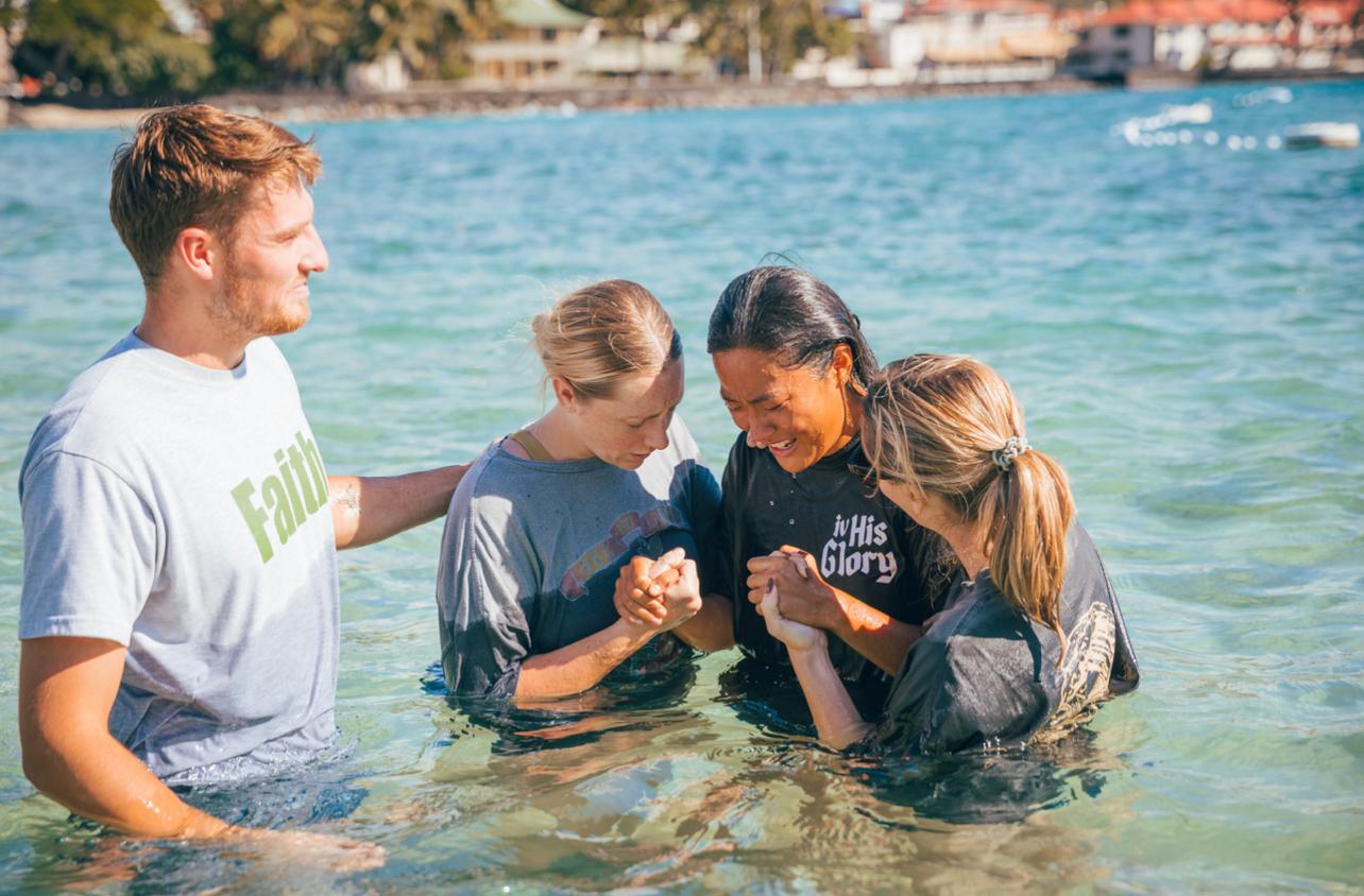 Belle Liu being baptized in the ocean, held up by fellow missionaries